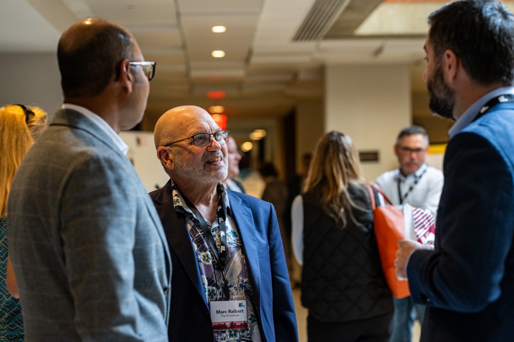 Impact speakers Shamim Mohammed, Marc Raibert, and Chris Townsend connect between sessions.
