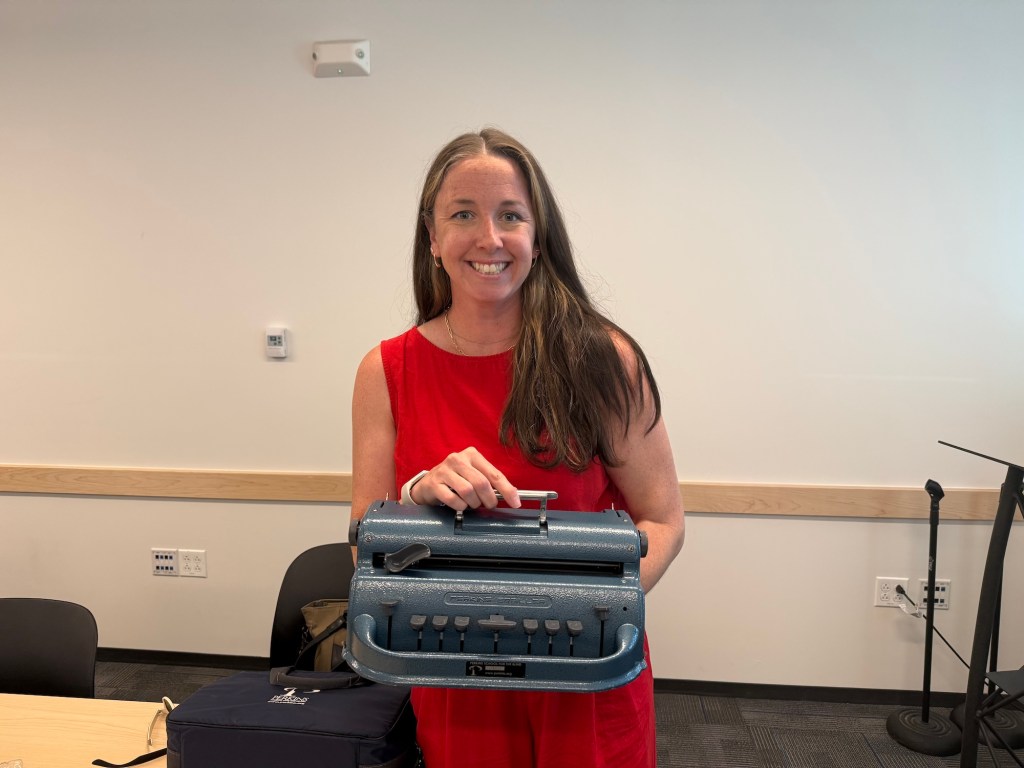 Meghan Gagne of Perkins School for the Blind holding an AI-enabled Braille machine.