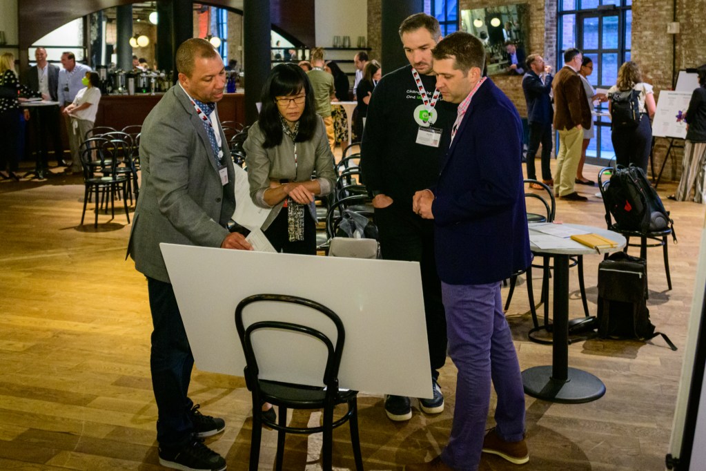 Several attendees interact with a station set up in a skill-building workshop about pushing long-standing organizations to adopt better transformational innovation strategies. Gina O’Connor, a Professor of Innovation at Babson College in Boston (not pictured), led the session.
